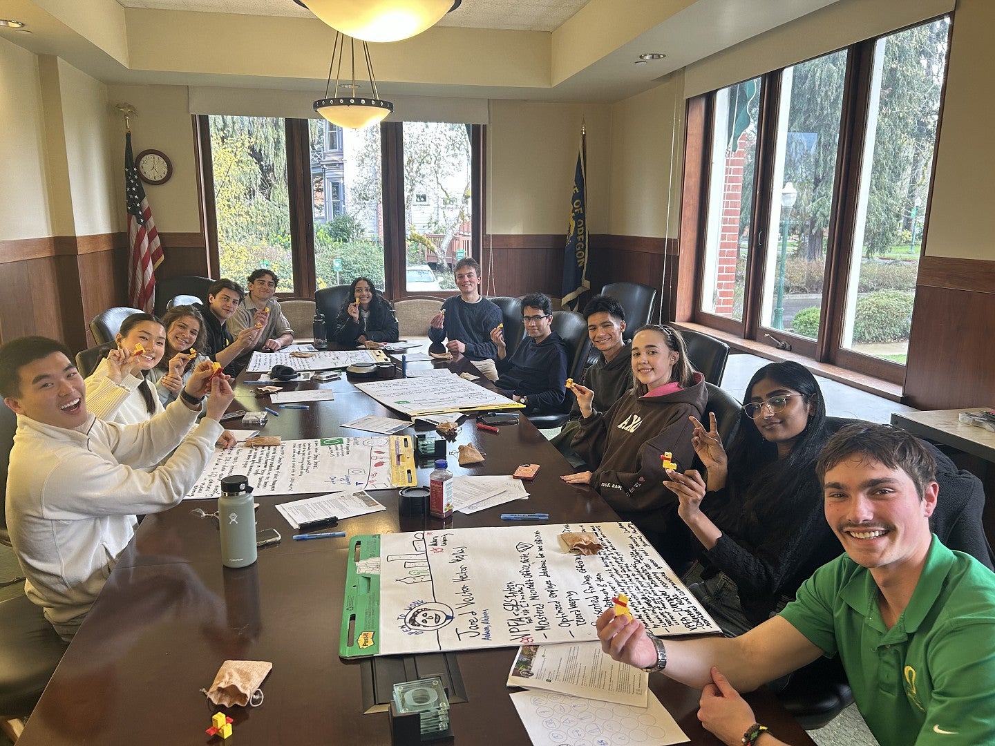 12 members of the 2024-25 cohort seated around a table holding up Lego ducks they had made 