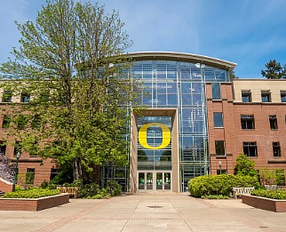 Large tree in front of Lillis business complex--lots of windows in the middle with the UO "O" in yellow; blue sky above