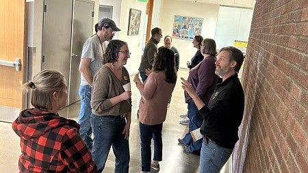 LEADS participants standing in a hallway talking animatedly in pairs