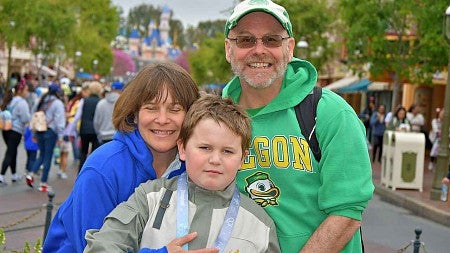 Kelly, her husband, and her son at Disneyland in 2025 - crowds and a castle in the background