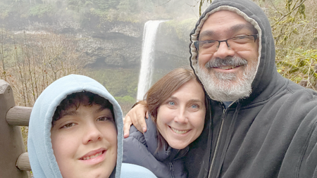 Philp, his wife, and son enjoying a rainy day at Silver Falls State Park - waterfall and greenery visible in the background
