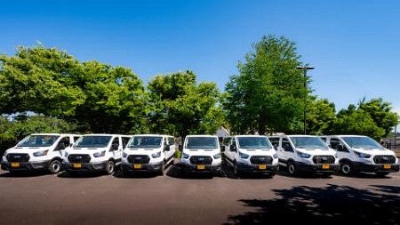 Seven vans parked in the Motor Pool lot