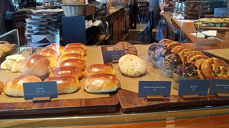 Assorted pastries including brioche, cookies, and muffins arranged behind glass