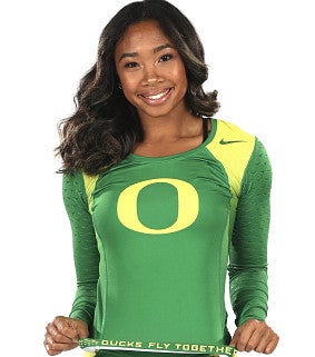 Woman with long black hair wearing a yellow and green sports outfit showing the "O" and "Ducks Fly Together" smiles in front of a white background