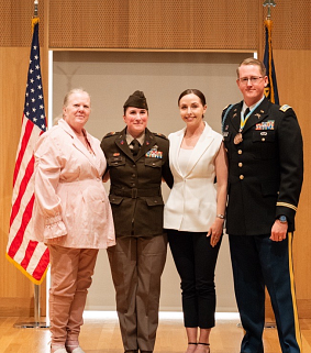 Elisabeth in military uniform standing next to an older woman and younger woman i civilian clothes, and a man in military uniform