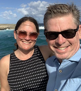 Renee and her husband Jeff at the coast - ocean and blue sky behind them