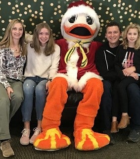 In the middle sits the UO Duck in Santa Claus attire; on the left sit a women and a girl; on the right sit Grant with a girl on his knee