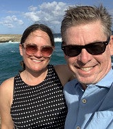 Renee and her husband Jeff at the coast - ocean and blue sky behind them