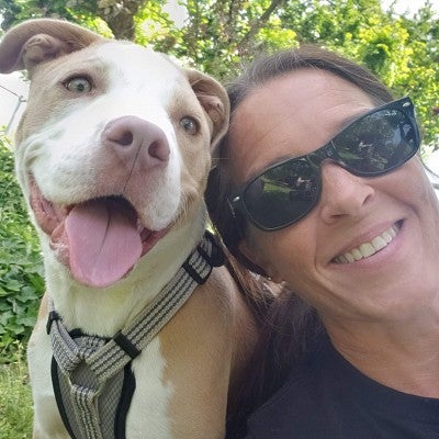 Kristy (wearing sunglasses) next to her brown and white dog, Corn