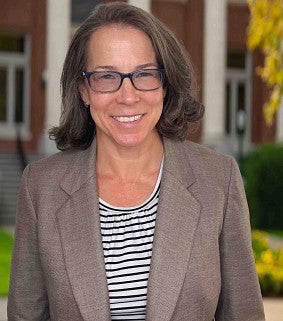Female with brown hair, glasses, heathered grey jacket 