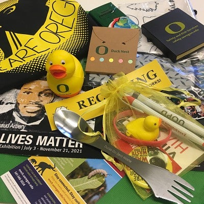 Assorted swag including a Tshirt, plastic ducks, pens, a flyer for a Black Lives Matter exhibition, a spork, stickers, and stationery from Duck Next and Safety and Risk Services